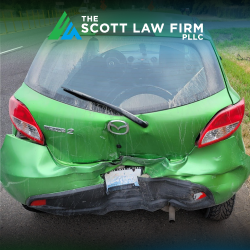 After a rear-end accident in Vancouver, a green car sits in the road with a smashed back end