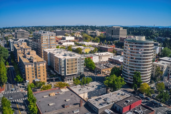 An aerial view of the Vancouver, Washington skyline featuring a prominent cylindrical building and modern apartments under a clear blue sky.