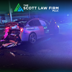 A car after a rear-end accident in Vancouver, with the glow of police lights in the background